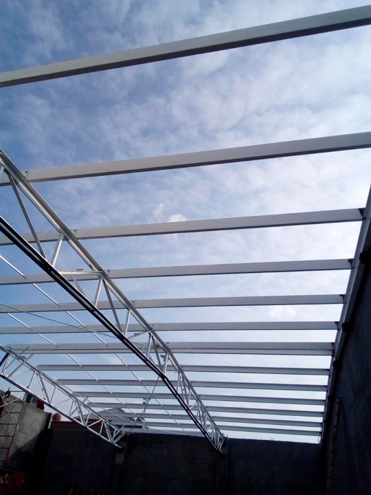 Armado de cubierta en estructura metálica de bodega para mueblería en proceso de construcción.