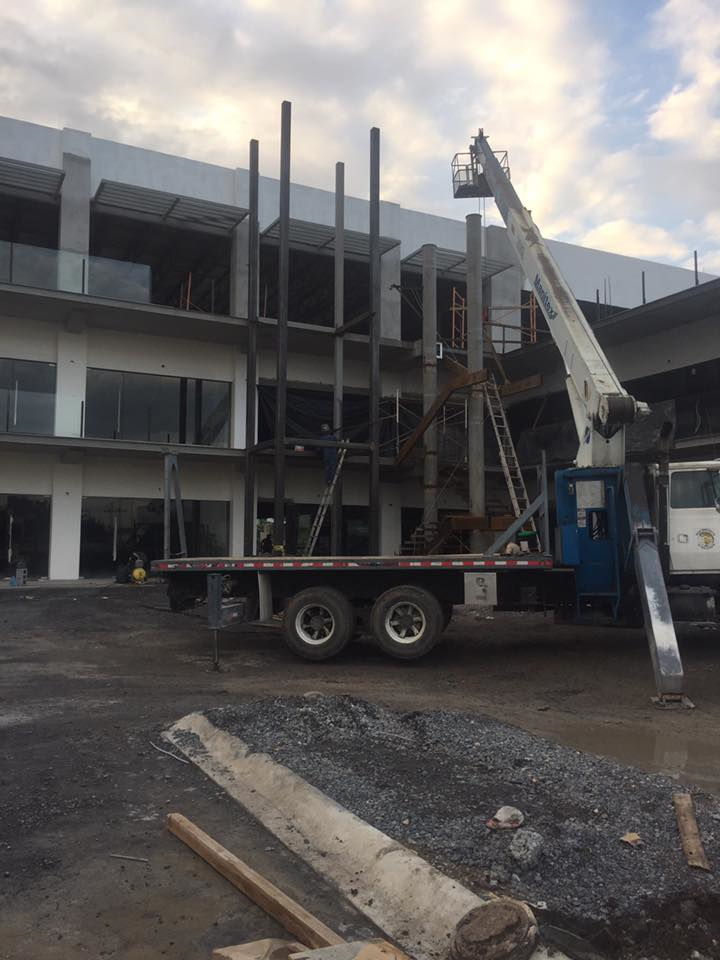 Montaje de estructura metálica de escaleras mediante camión grúa en edificio comercial.