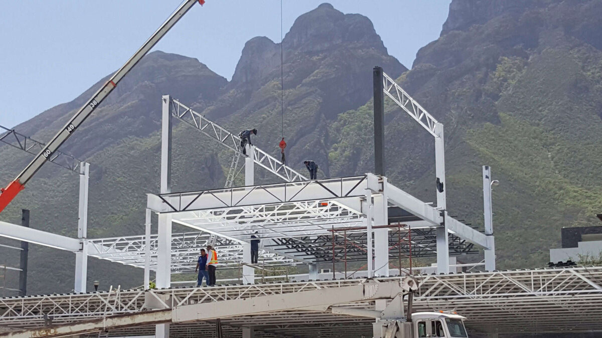 Montaje de estructura metálica de plaza comercial mediante grúa.